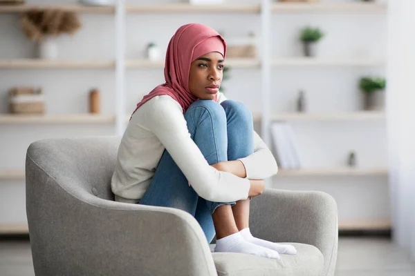 Concetto di solitudine. Depresso africano islamico signora seduta in sedia a casa — Foto Stock