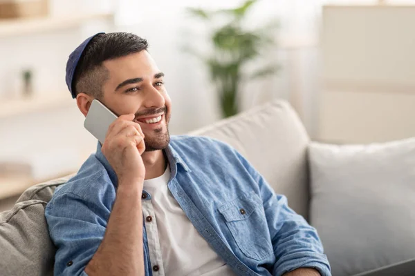 Homme millénaire souriant parlant au téléphone à la maison — Photo