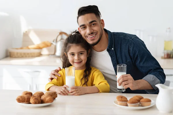 Portrét šťastného arabského otce a malé dcery jedení občerstvení v kuchyni — Stock fotografie