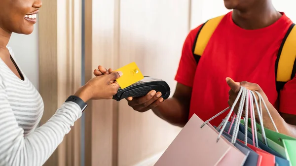 Africká žena provedení platby kreditní kartou na dodání Indoors — Stock fotografie