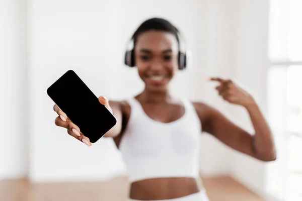 Felice donna nera sportiva che punta al telefono con schermo bianco — Foto Stock