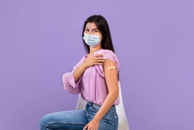 Coronavirus aşısı. Aşılanmış, koruyucu maskeli Ermeni kadının portresi yapışkan bantla elini gösteriyor.