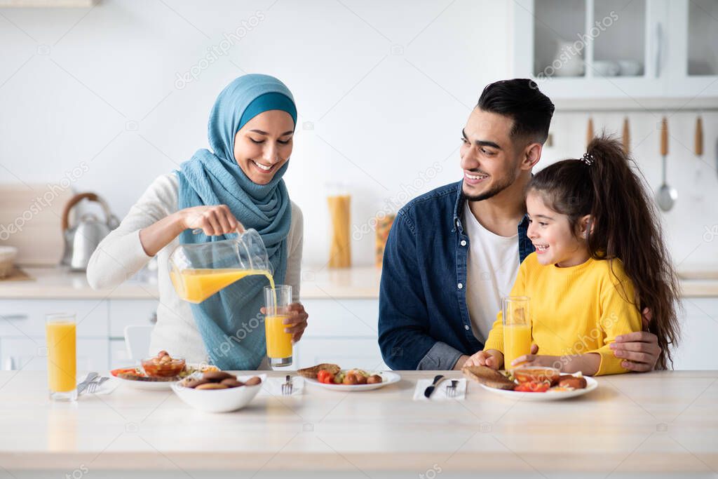 Happy Islamic Family With Little Daughter Having Tasty Lunch In Kitchen Together