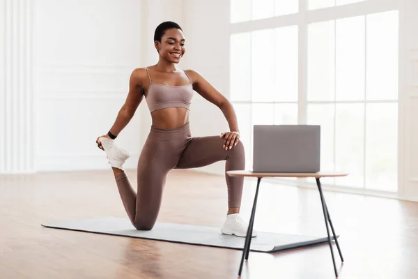 Sorridente donna africana in abbigliamento sportivo facendo gambe quad stretching esercizio — Foto Stock