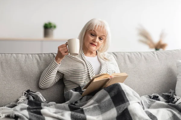 Donna anziana felice che si riposa a casa, leggendo libro — Foto Stock