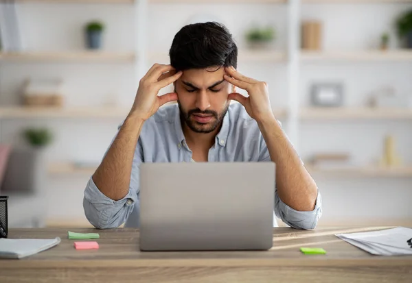 Deadline stress. Annoyed arab guy looking at laptop screen while sitting at workplace at home office — Stock Photo, Image