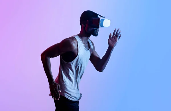 Zijaanzicht van duizendjarige zwarte atleet in VR-headset uitgevoerd in neon verlichting. Moderne technologieën in de sport — Stockfoto