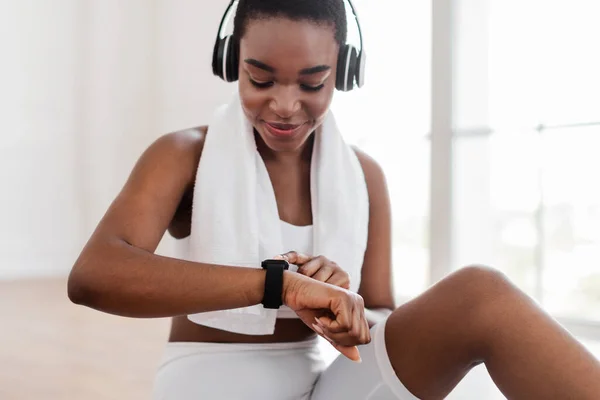 Sporty African woman checking fitness tracker during workout break — Stock Photo, Image