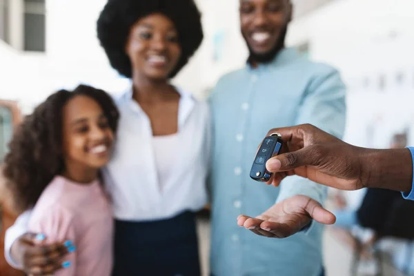 Gerente dando a chave do carro novo à família preta nova na loja da concessionária do automóvel, foco seletivo — Fotografia de Stock