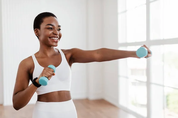 Afro sportovní žena cvičení se dvěma činkami a pózování — Stock fotografie