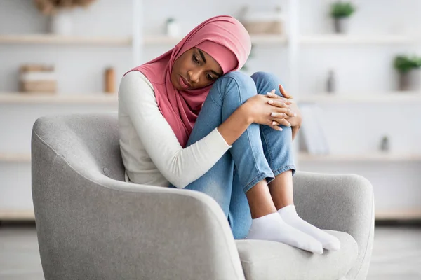 Concepto de melancolía. Deprimida mujer negra musulmana en hiyab sintiéndose molesta en casa — Foto de Stock