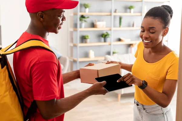 Dame ontvangt pakketje van koerier scannen vingerafdruk Via Tablet Indoor — Stockfoto