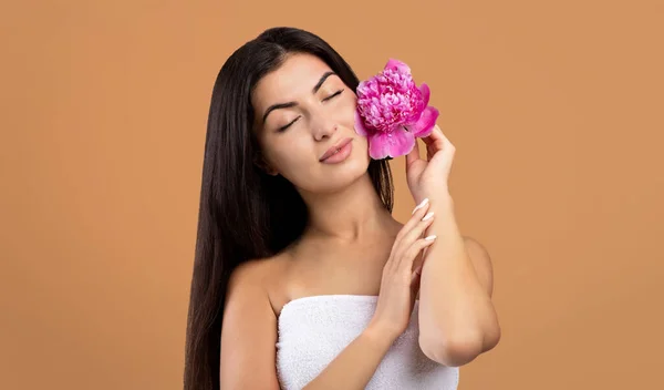 Beleza e bem-estar. Mulher arménia bonita segurando peônia bonita e fechar os olhos, posando no fundo marrom — Fotografia de Stock