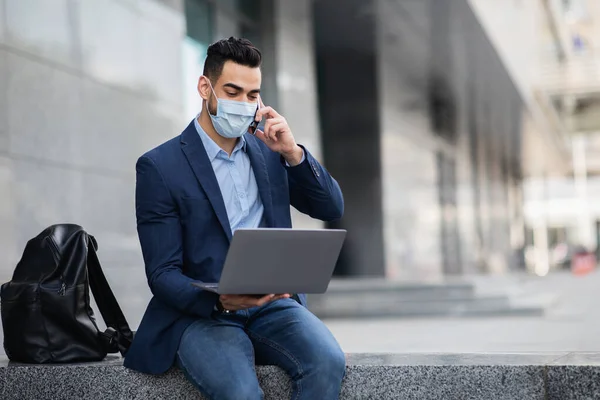 Árabe CEO em máscara facial com laptop ter conversa telefônica — Fotografia de Stock