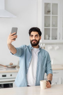 Arap blogcu sosyal medya için video ya da fotoğraf çekiyor. Akıllı telefon tutan, selfie çeken, mahsul alan genç bir adam.