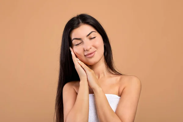 Concepção de elevação facial. Mulher arménia feliz com os olhos fechados tocando pele macia em suas bochechas sobre fundo bege — Fotografia de Stock