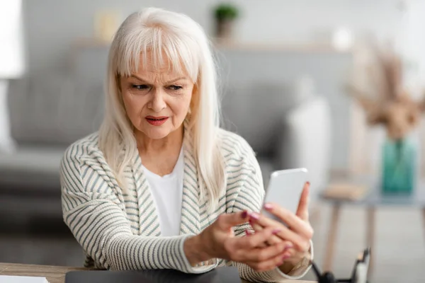 Confuso donna anziana utilizzando il suo telefono cellulare — Foto Stock