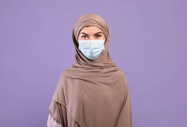 코로나 바이러스의 개념. 보호용 마스크를 쓰고 있고, 자주 색 스튜디오 배경 위에서 있는 히잡에 있는 여성 을묘 사 한 그림 — 스톡 사진