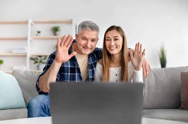 Casal maduro alegre chamando seus amigos na webcam, conversando com a família remotamente de casa, acenando para a câmera — Fotografia de Stock