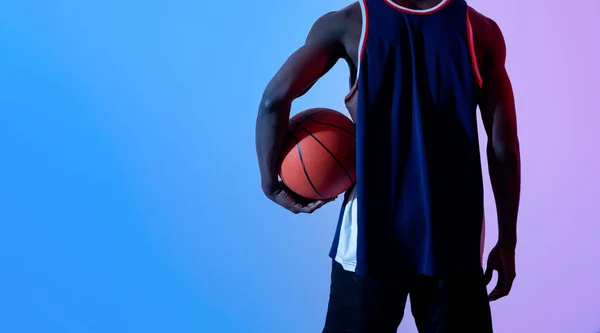 Unrecognizable black basketball player holding ball in neon light, banner design with copy space — Stock Photo, Image