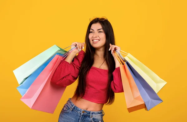 Säsongsförsäljning. Porträtt av glad armenia kvinna som håller färgglada shoppingpåsar med inköp, gul bakgrund — Stockfoto