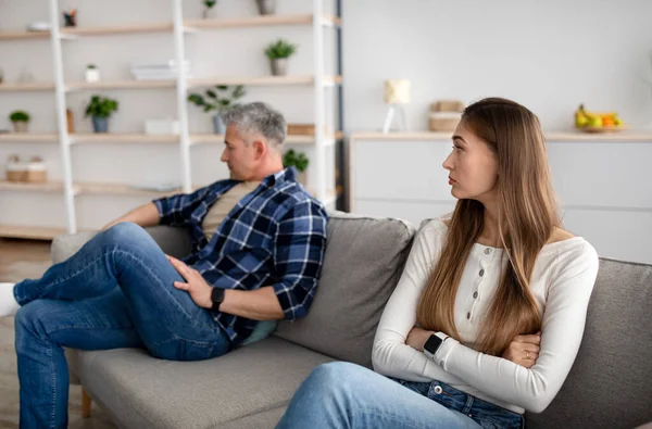 Зріла жінка і її чоловік сидять на дивані вдома після сварки, почуваючись ображеними, маючи конфлікт — стокове фото