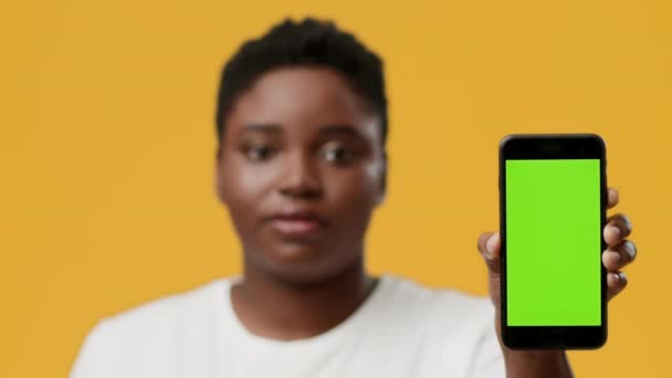 Μαύρη γυναίκα που παρουσιάζει Smartphone με Chroma βασική οθόνη, κίτρινο φόντο — Αρχείο Βίντεο