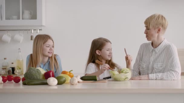 Mère heureuse et deux filles cuisiner et parler dans la cuisine — Video