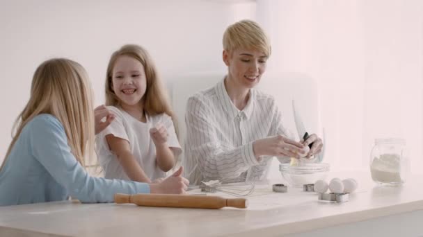 Mãe e filhas fazendo biscoitos se divertindo com farinha interior — Vídeo de Stock