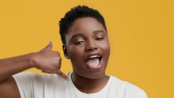 Plus-size Black Lady Gesturing Bel me poseren over gele achtergrond — Stockvideo