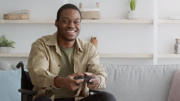 Freudiger behinderter Afroamerikaner spielt und gewinnt Videospiel drinnen — Stockvideo