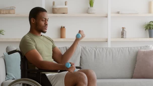 Homme afro-américain handicapé en fauteuil roulant s'exerçant avec des haltères à l'intérieur — Video