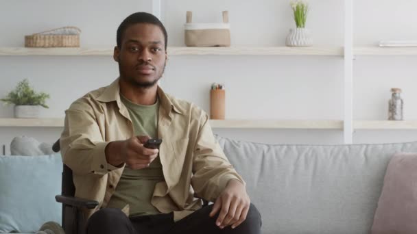 Descontento deshabilitado negro chico viendo canales de conmutación de TV en casa — Vídeos de Stock