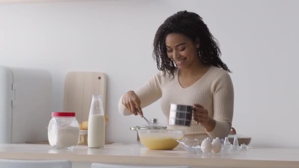 Buona cottura. Giovane casalinga afro-americana positiva che cucina pasta in cucina e danza, aggiungendo farina alla ciotola — Video Stock