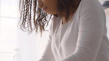 Yemek pişirme süreci. Yoğunlaşmış genç Afro-Amerikan ev kadınının başından sonuna kadar ateş edilmiş.