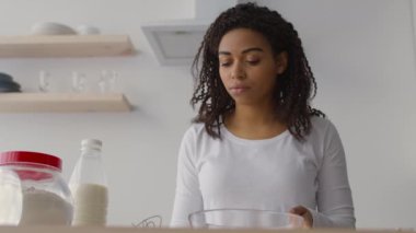 Mutfak işleri. Afro-Amerikalı genç bayan hamur işlerine süt ekliyor.