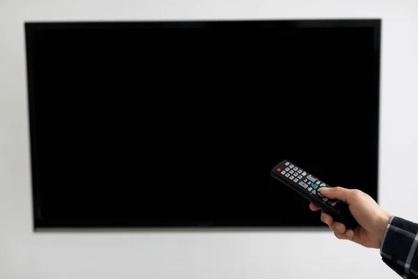 Pusty ekran telewizora i ręka z pilotem telewizyjnym w pomieszczeniu — Zdjęcie stockowe