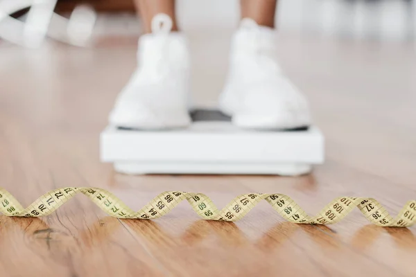 Primo piano nero donna in piedi su scale, concentrarsi su misura nastro — Foto Stock