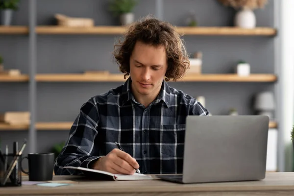 Homme d'affaires sérieux travaillant sur ordinateur portable prenant des notes au bureau — Photo