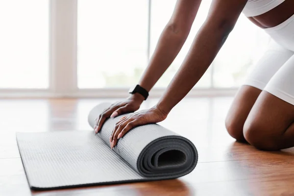 Joven mujer negra desenrollando esterilla de yoga en el suelo —  Fotos de Stock