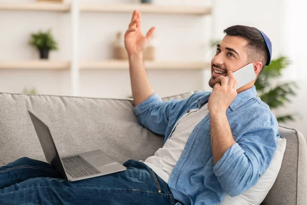 Guy utilisant un ordinateur et parlant sur un téléphone portable à la maison — Photo