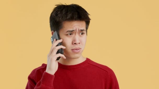 Discontented Chinese Guy Talking On Cellphone Frowning Over Yellow Background — Stock Video