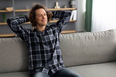 Mutlu adam koltukta oturup gülümsüyor.