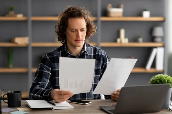 Entrepreneur Guy Holding Papers Reading Business Reports In Office