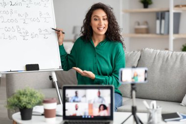 Matematik öğretmeni tahtayı gösteriyor, öğrencilere sanal konferans veriyor
