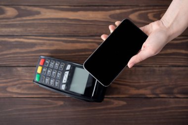 Modern kolay NFC teknolojisi kullanılarak akıllı telefondan ödeme yapan müşterilerin en üst görünümü, cep telefonunu boş ekran ile tutmak