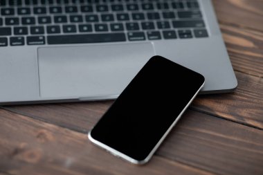 Bilgisayarın yanına siyah ekranlı modern akıllı telefon, yakın plan. Tasarımınız veya reklamınız için bir model