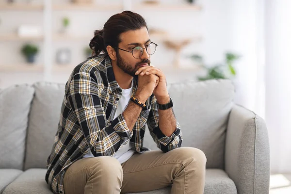 Pensiv arabiska killen sitter på soffan hemma — Stockfoto