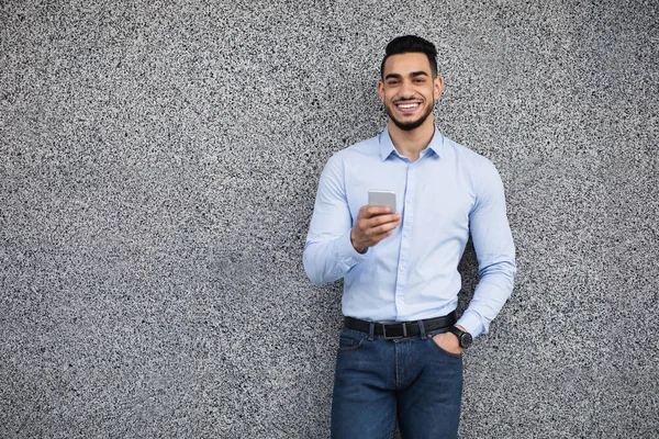 Good-looking arab guy in formal wear standing over grey wall