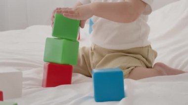Bebek, evde, yatakta otururken blok yapmakla uğraşıyor.